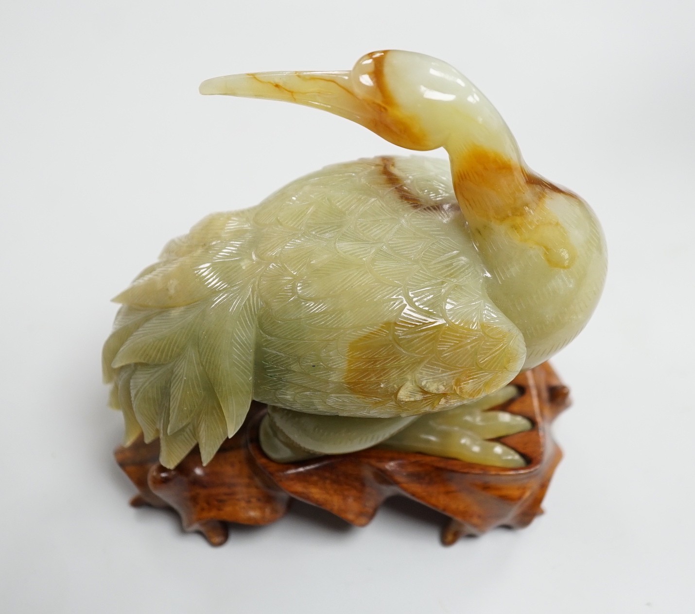 A Chinese green and russet jade figure of a crane, 11.5cm long, wood stand